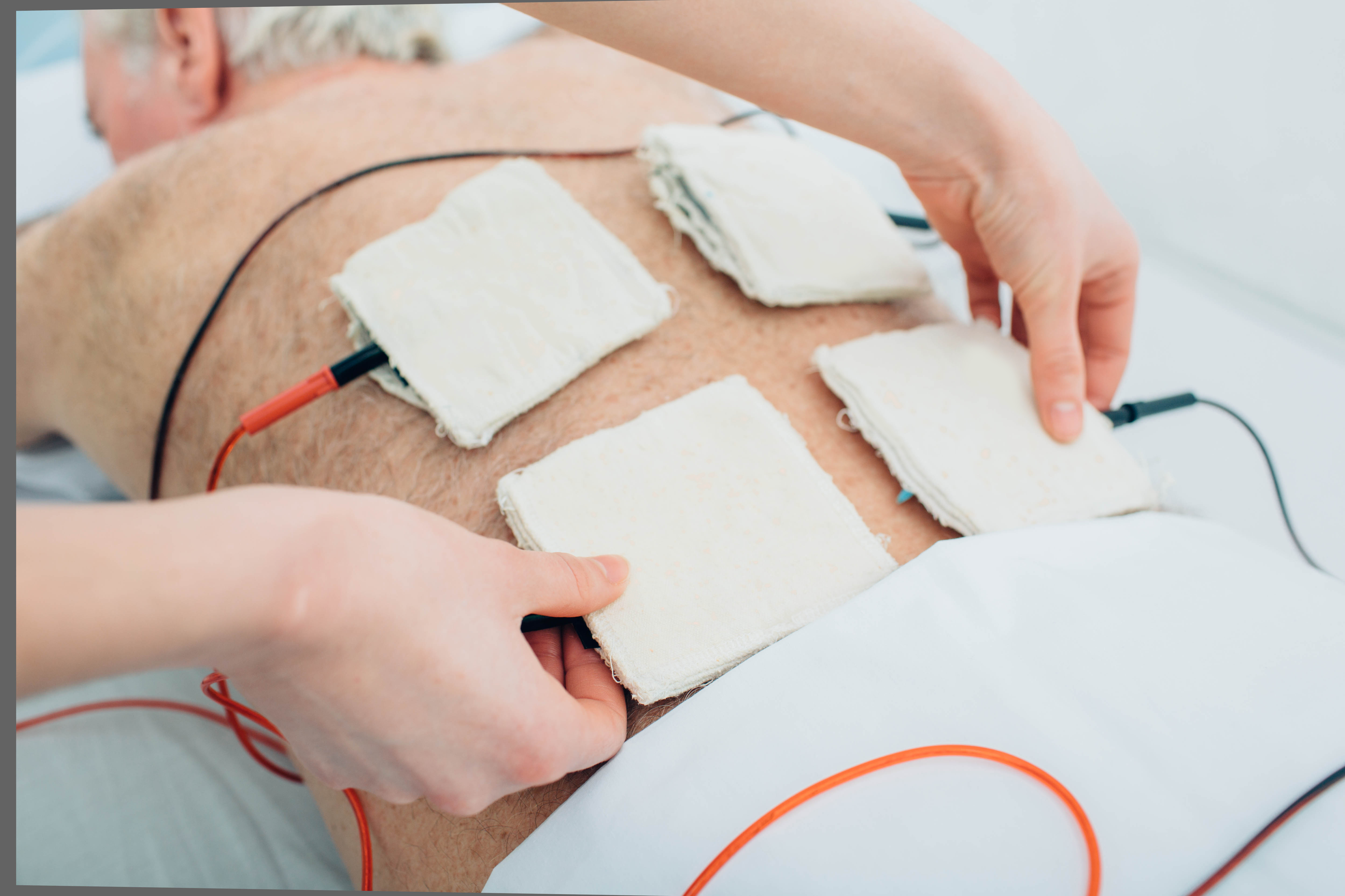 Persona relajada en clínica mientras recibe un tratamiento de microcorrientes para el dolor en la espalda, ambiente luminoso y profesional